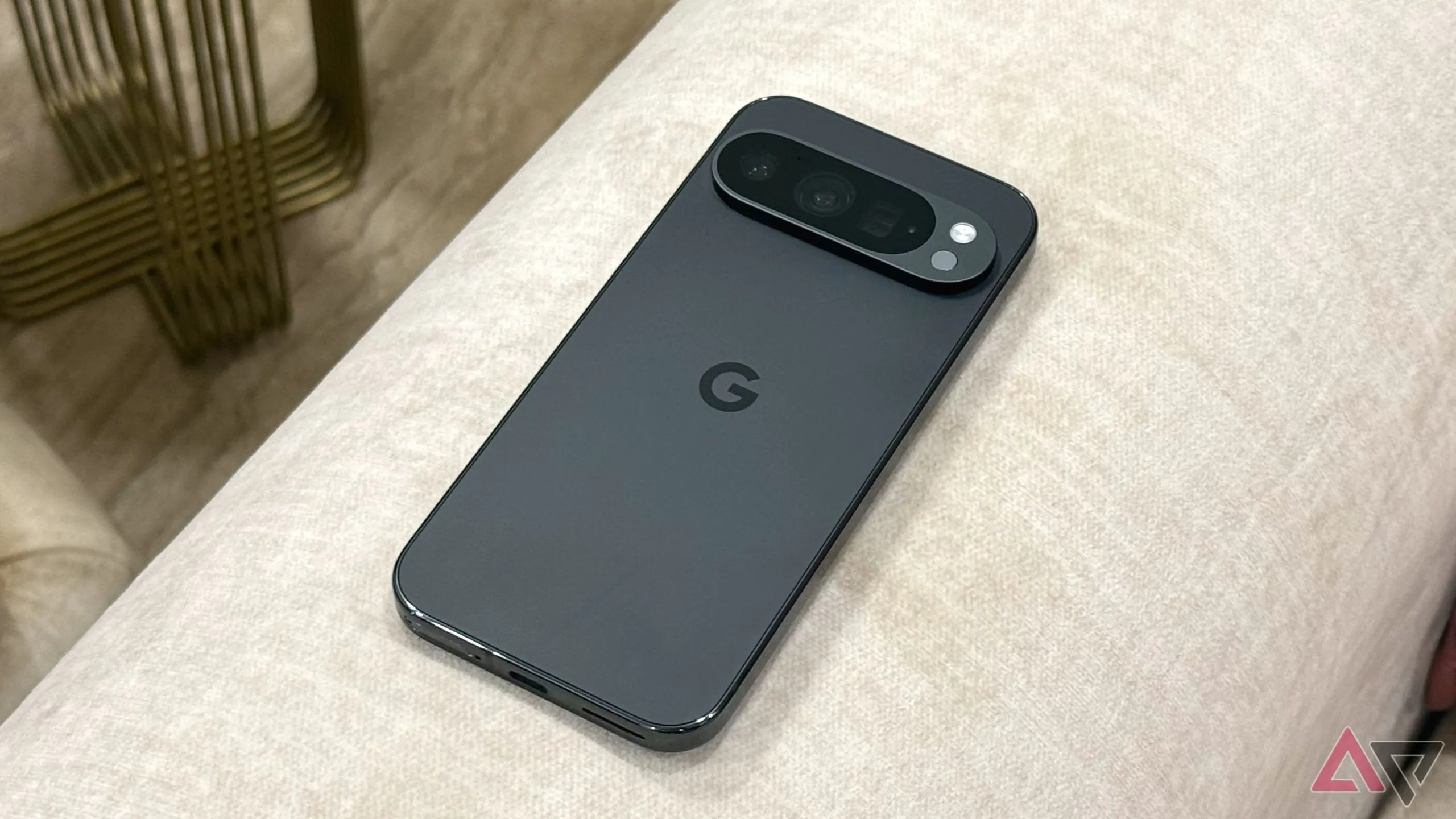 Điện thoại Google Pixel 9 Pro màu xanh bạc hà đặt nghiêng trên ghế sofa, hiển thị màn hình khóa.