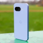 Điện thoại Google Pixel 9a màu tím đặt đứng trong công viên, mặt lưng hướng về phía trước.