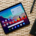 Điện thoại Google Pixel Fold đặt trên bàn mây tre cùng sổ tay và bút