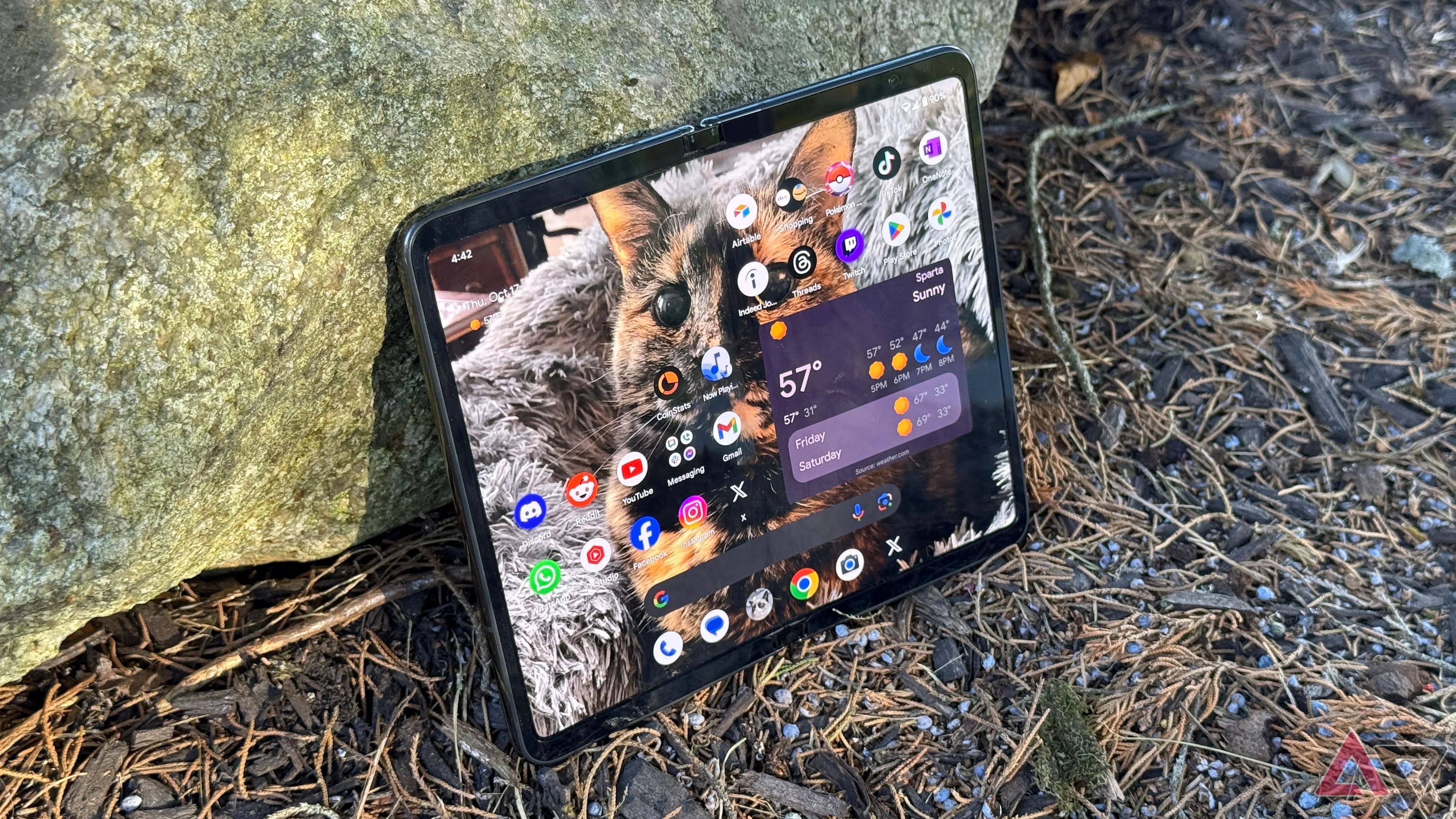 Điện thoại Google Pixel Fold màu đen tựa vào tảng đá trong khung cảnh ngoài trời