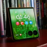 Điện thoại Moto Razr Ultra 2025 với màn hình ngoài đang hiển thị, đặt trên giá sách