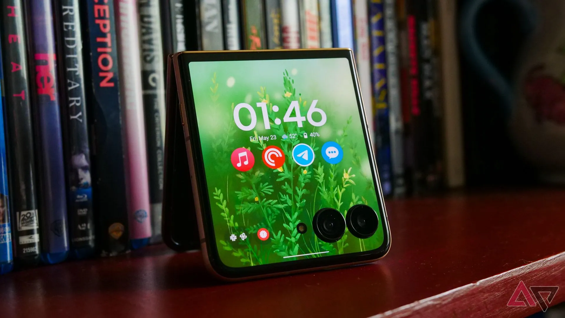 Điện thoại Motorola Razr Ultra 2025 với màn hình ngoài đang bật, đặt trên kệ sách