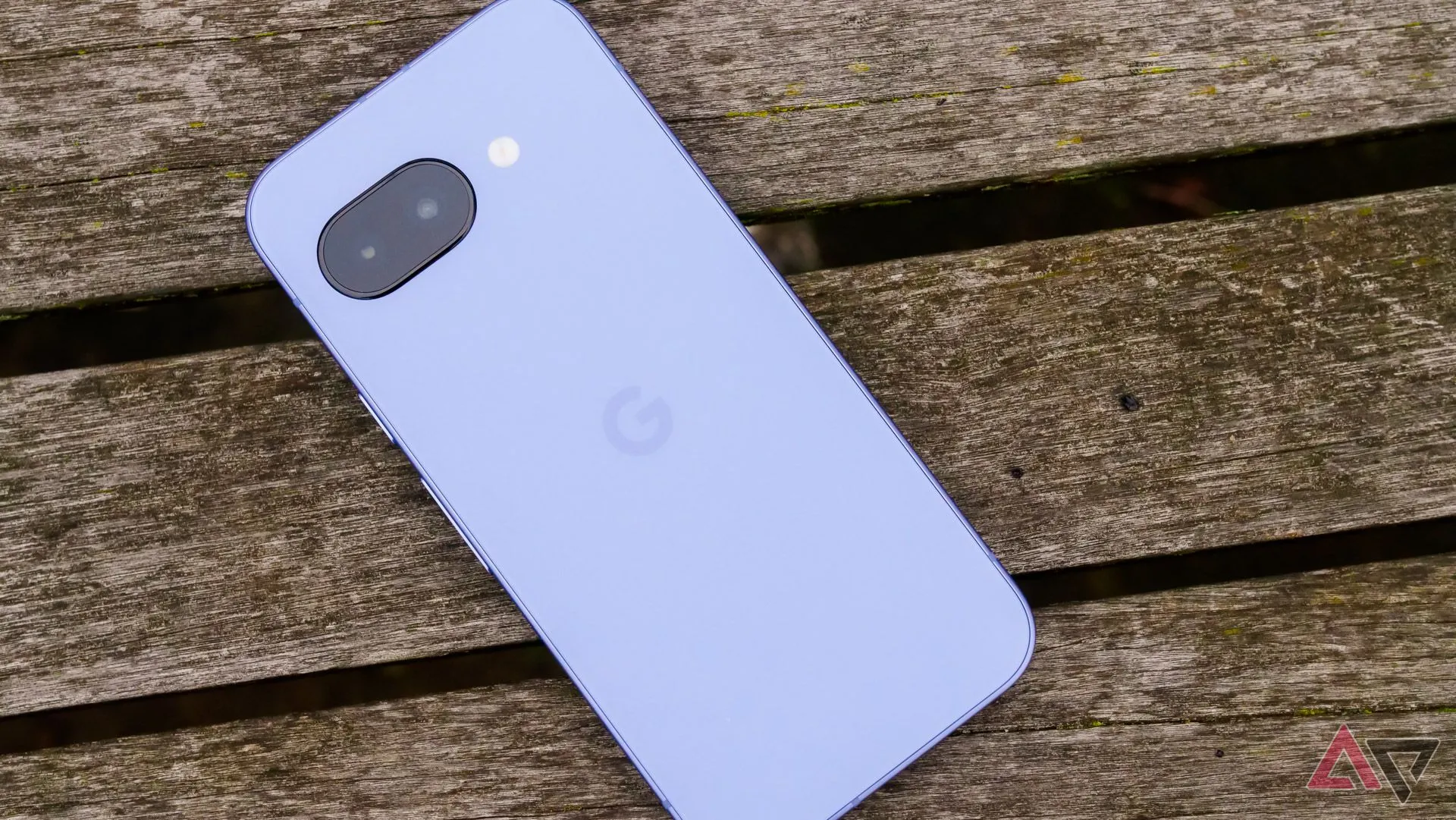 Điện thoại Pixel 9a đặt úp mặt trên ghế gỗ, thấy rõ cụm camera.