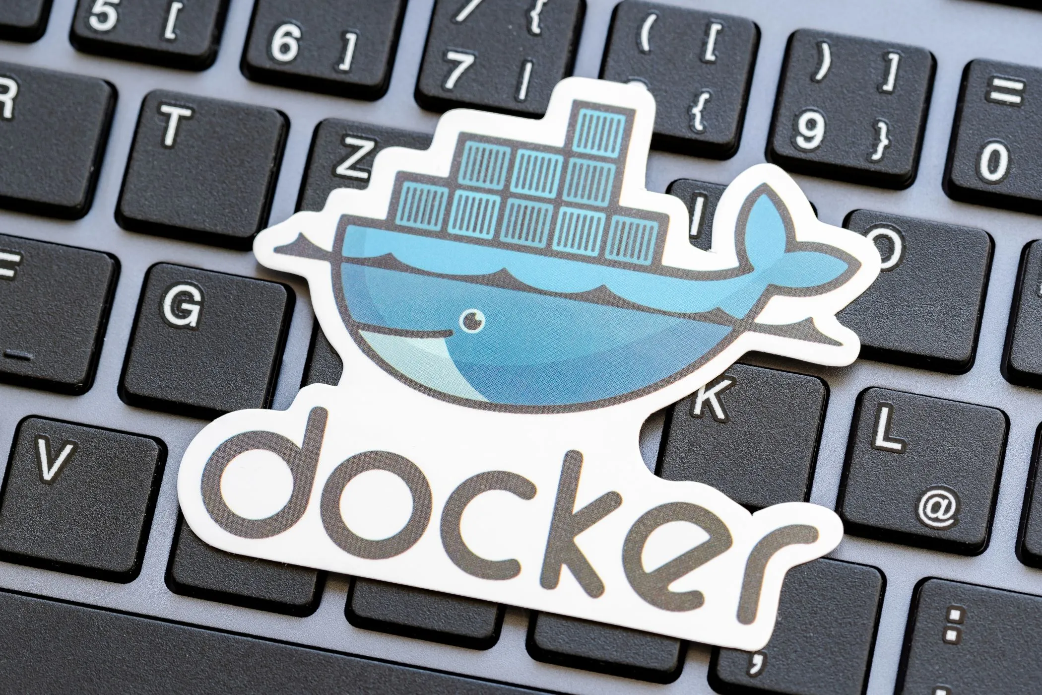 Logo Docker nổi bật trên nền bàn phím laptop, biểu tượng cho công cụ giúp việc tự host (self-hosting) trở nên dễ dàng hơn.