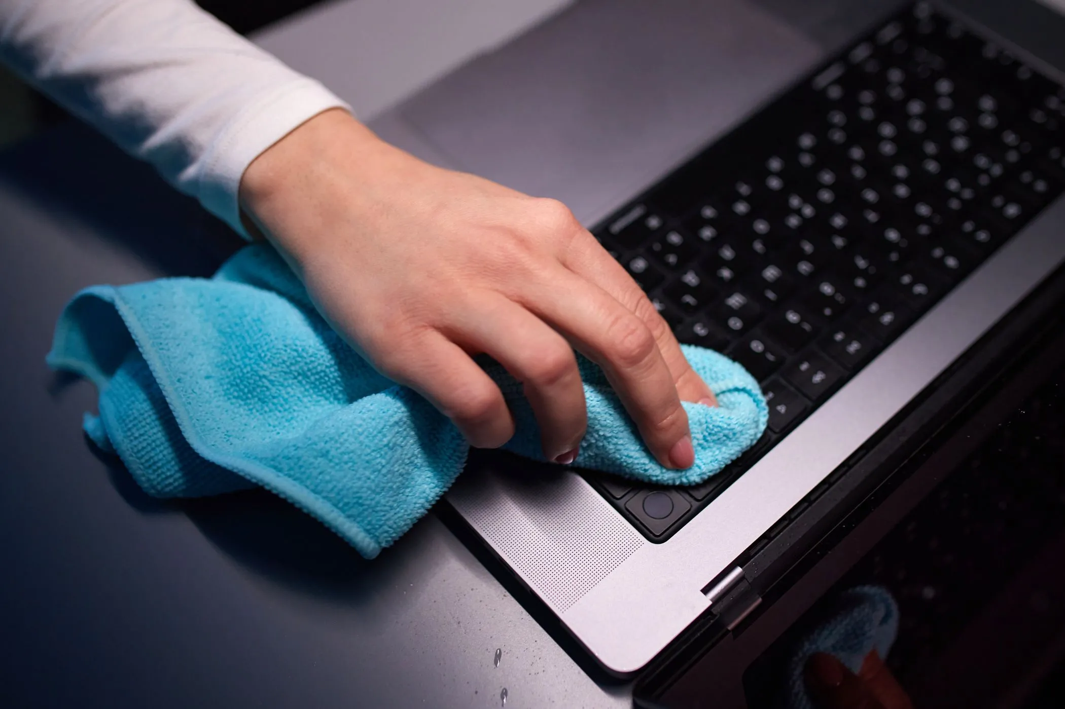 Một người đang dùng vải microfiber để vệ sinh màn hình MacBook Pro, minh họa cách làm sạch thiết bị trước khi bán.