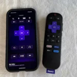 Người dùng cầm điều khiển Roku Express 4K Plus và xem giao diện trên màn hình TV