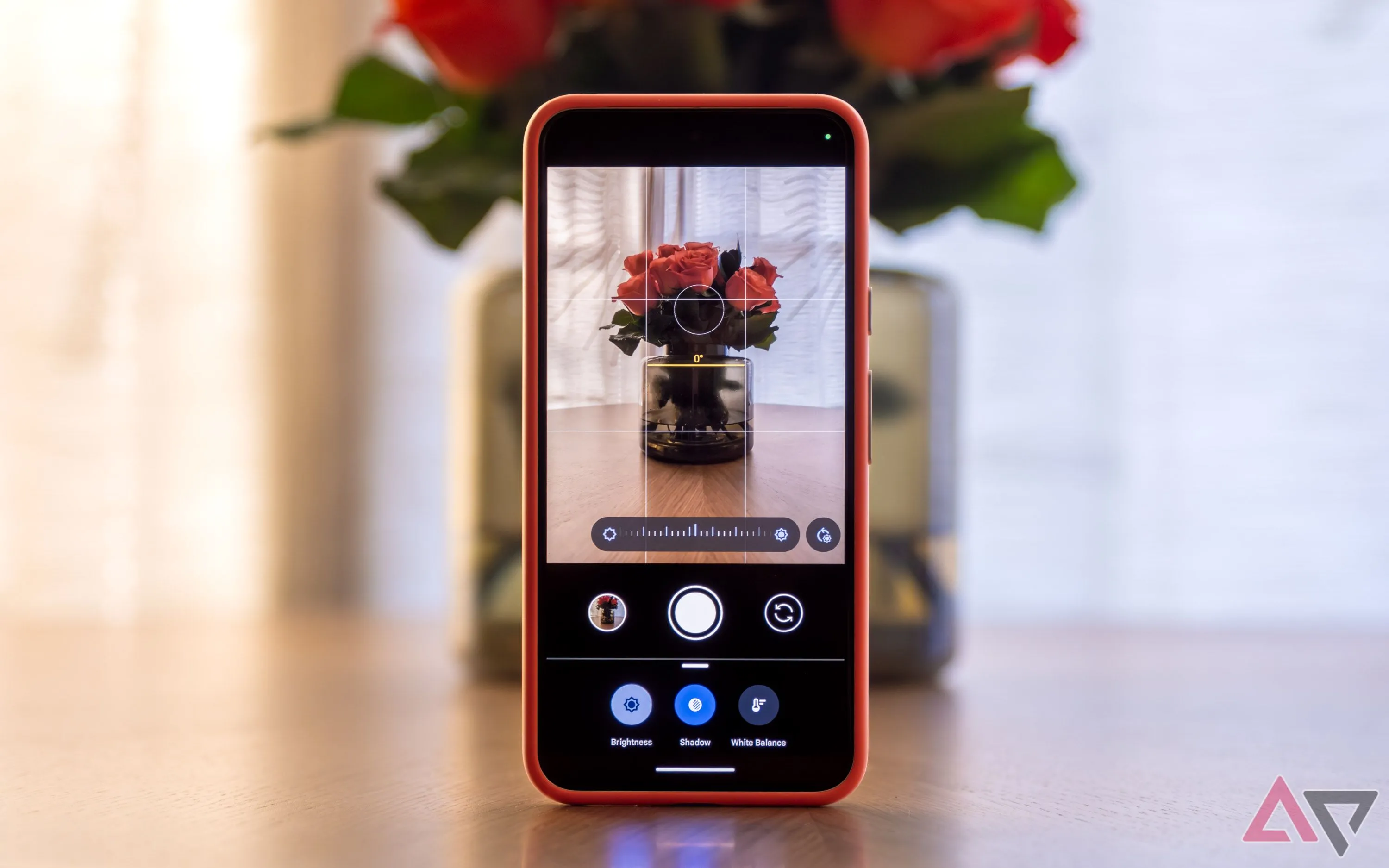 Ứng dụng Camera trên điện thoại Pixel đặt thẳng đứng trên bàn với lọ hoa, hiển thị hướng dẫn căn chỉnh Framing Hints