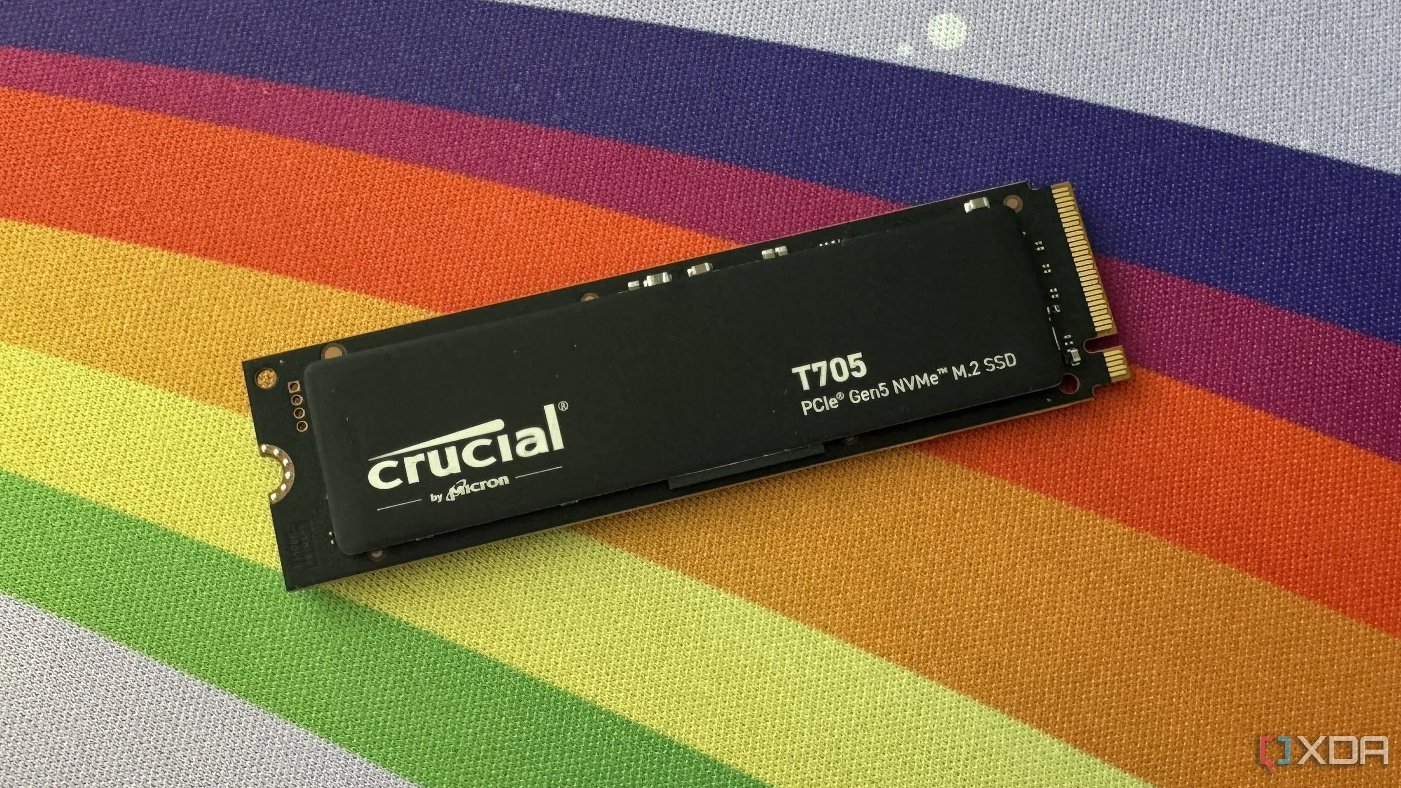 Ổ cứng SSD Crucial T705 PCIe Gen5 tốc độ cao đặt trên thảm bàn gaming đầy màu sắc