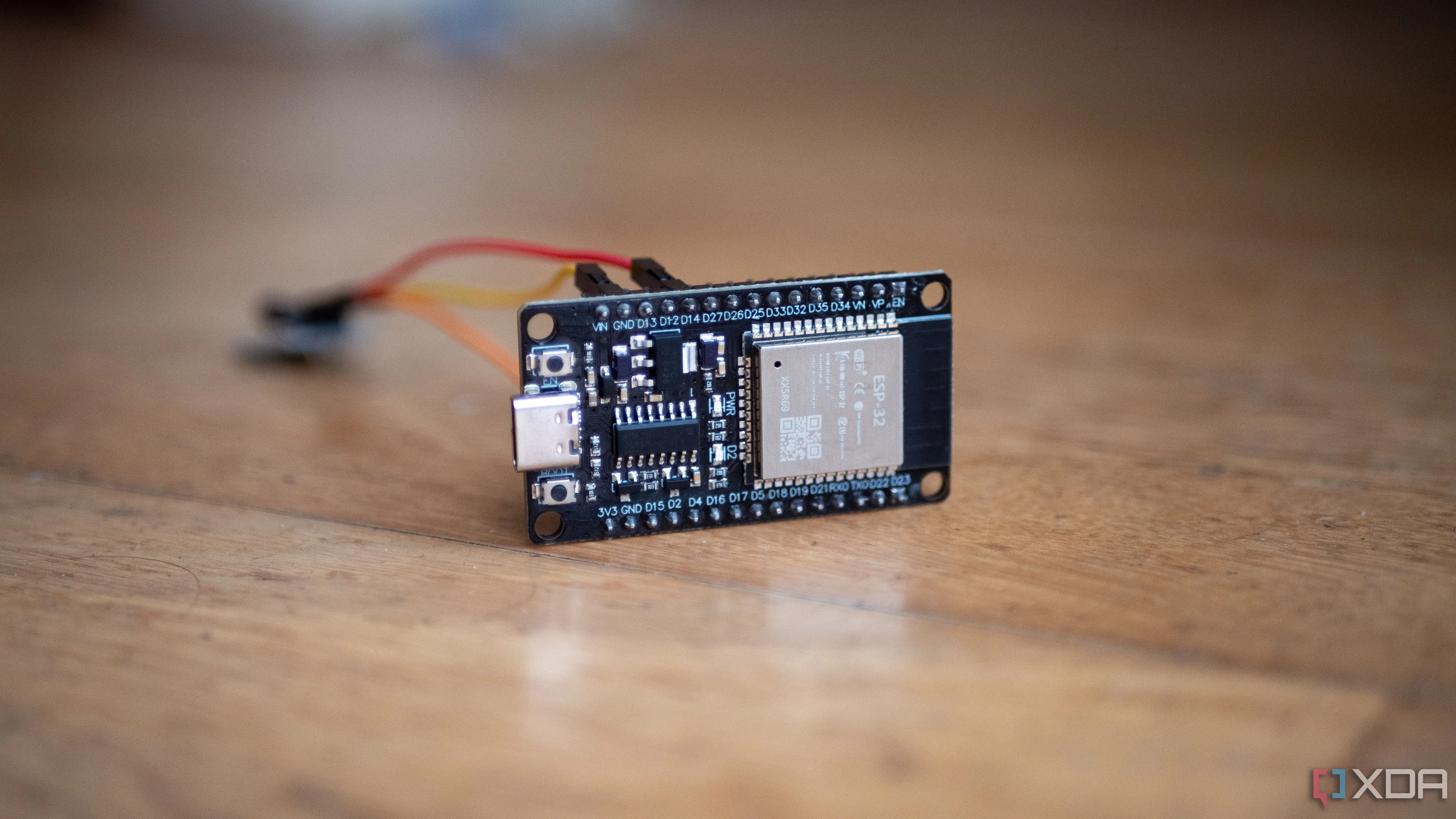 Vi điều khiển ESP32 được kết nối với cảm biến rung bằng dây nhảy trên bàn, minh họa khả năng mở rộng phạm vi Bluetooth cho Home Assistant