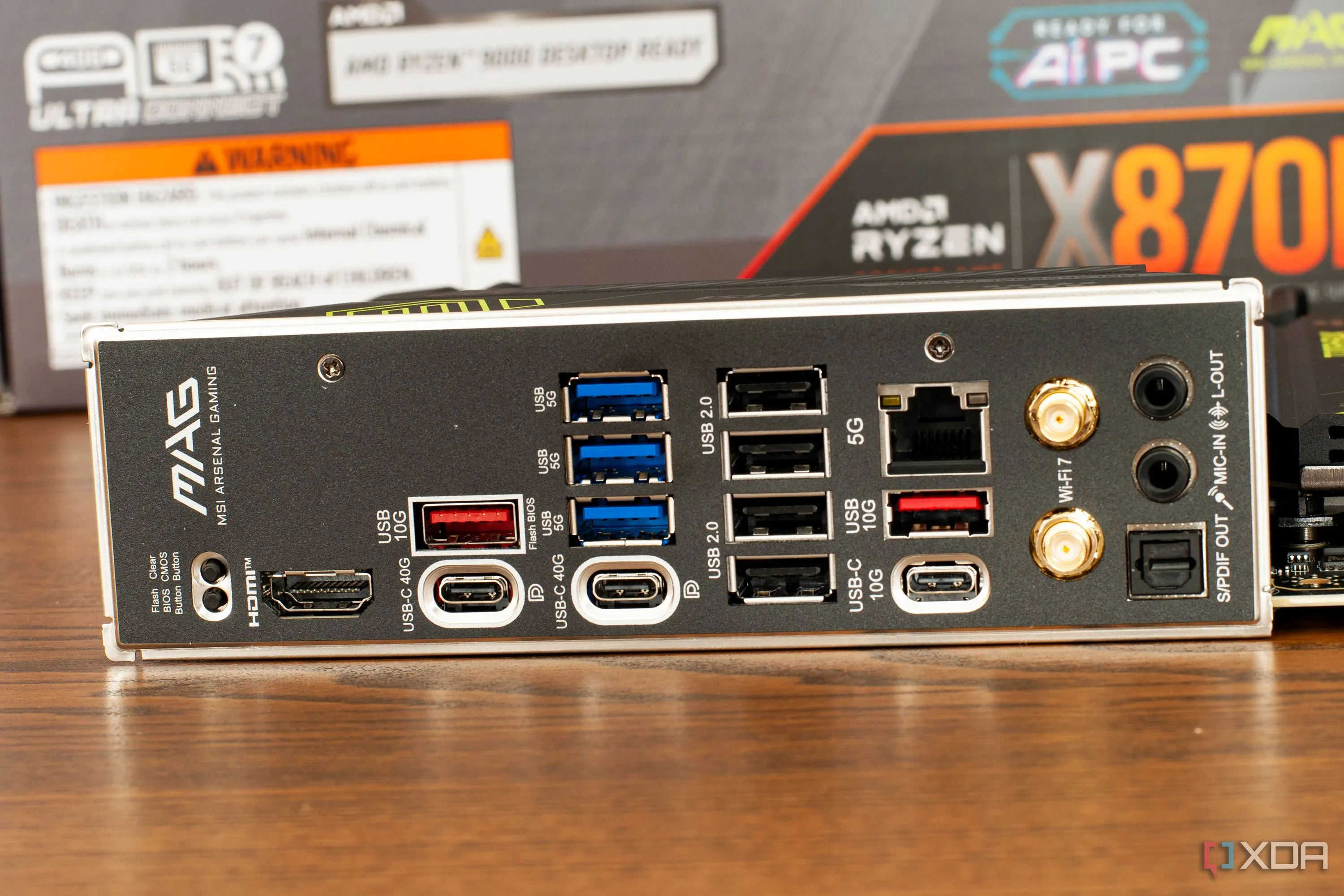 Bo mạch chủ MSI hiện đại với nhiều khe cắm RAM và dãy cổng I/O phía sau đa dạng, đang được đặt trên bàn