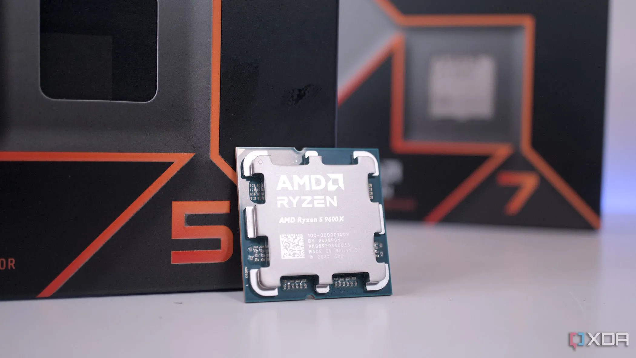 Bộ xử lý AMD Ryzen 5 9600X đặt trước hộp Ryzen 7 9700X, thể hiện sự khác biệt về kích thước và thương hiệu