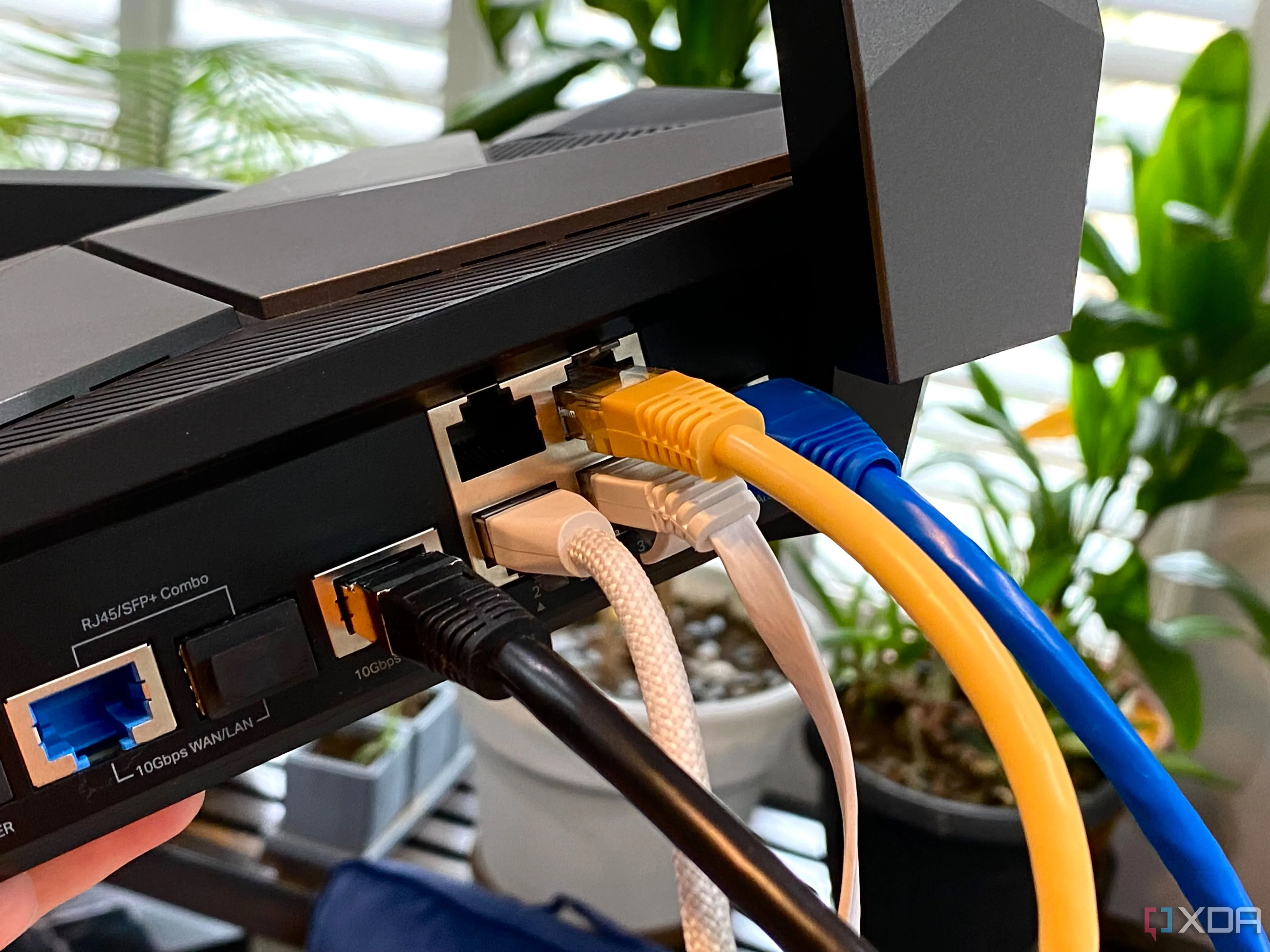 Các loại cáp Ethernet nhiều màu sắc cắm vào router TP-Link Archer AXE300, biểu trưng cho kết nối mạng vật lý và quản lý dễ dàng