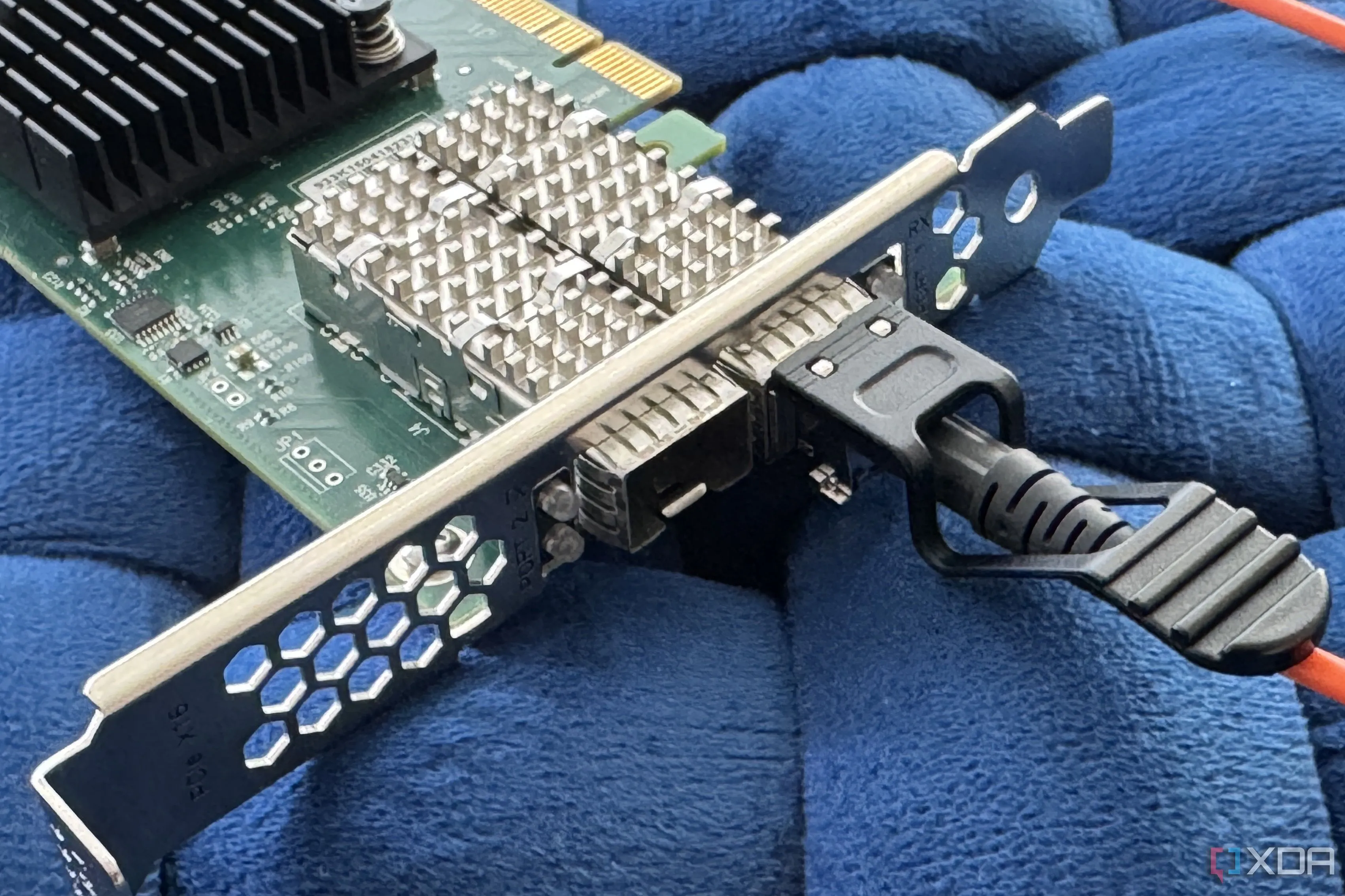 Cáp quang DAC (Direct Attach Cable) đang được cắm vào cổng mạng SFP+, biểu tượng cho kết nối 10GbE hoặc cao hơn.