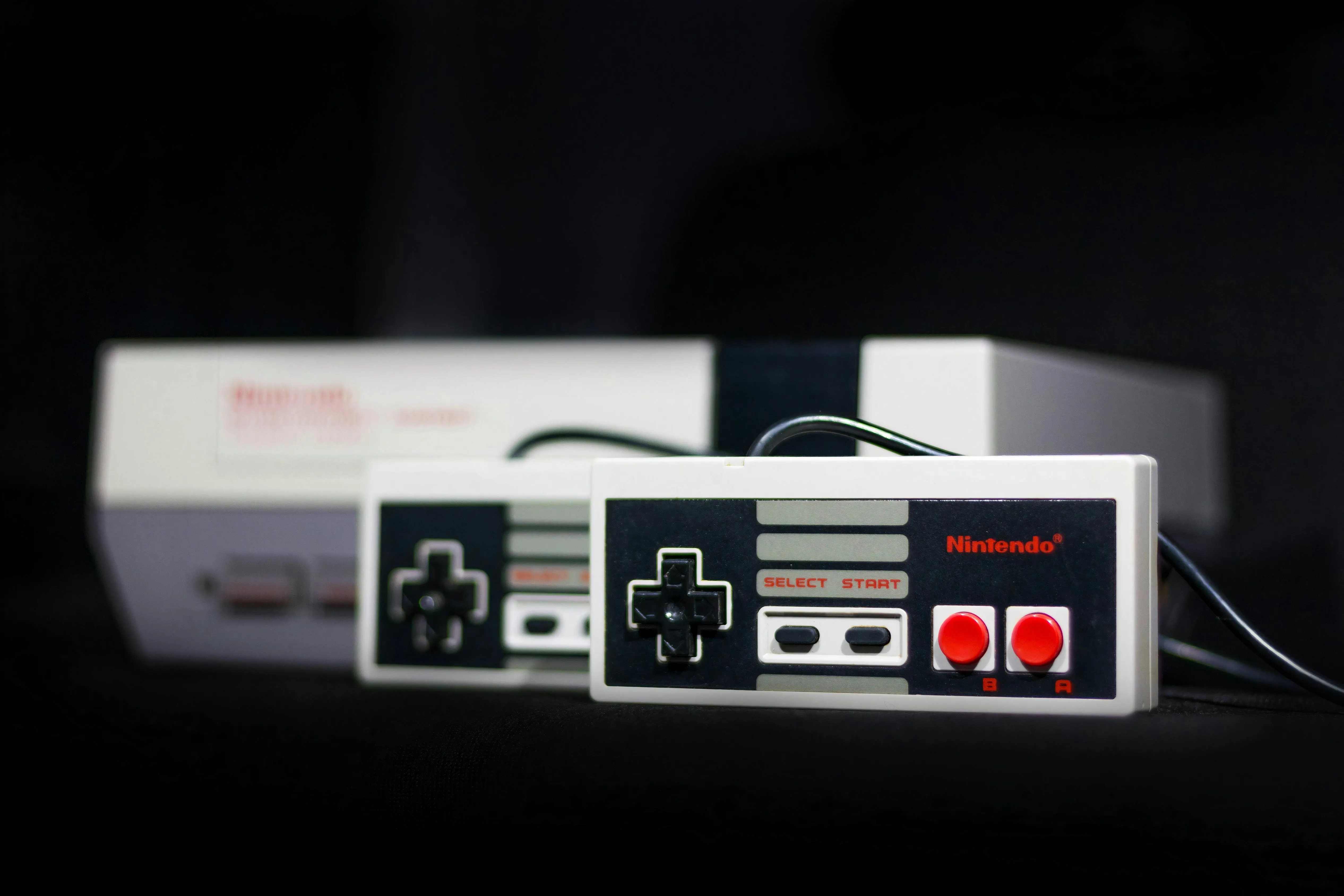 Chiếc máy chơi game Nintendo Entertainment System (NES) cổ điển trên nền tối, biểu tượng một thời của ngành game