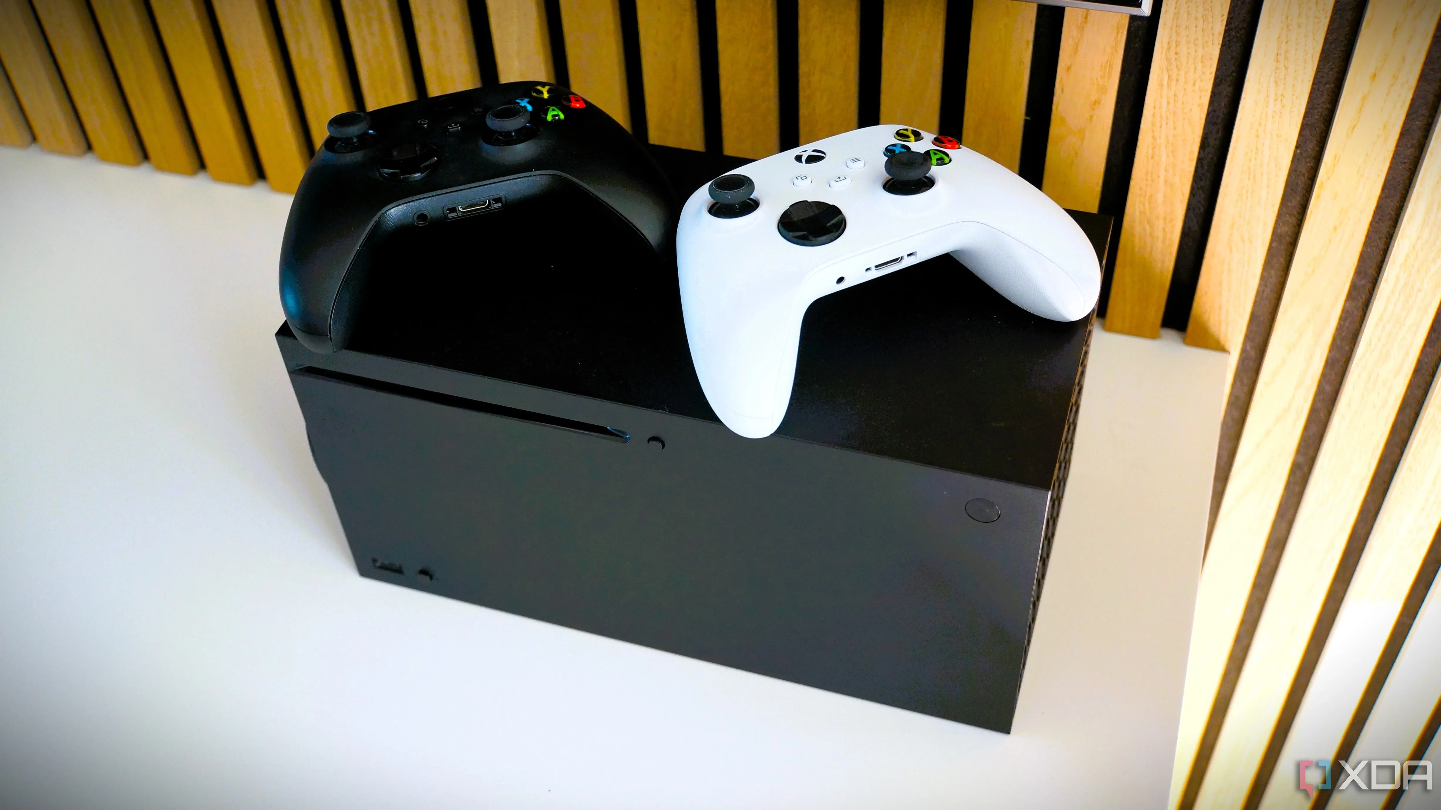 Console Xbox Series X với tay cầm màu đen và tay cầm màu trắng, minh họa về khả năng tương thích ngược của Xbox