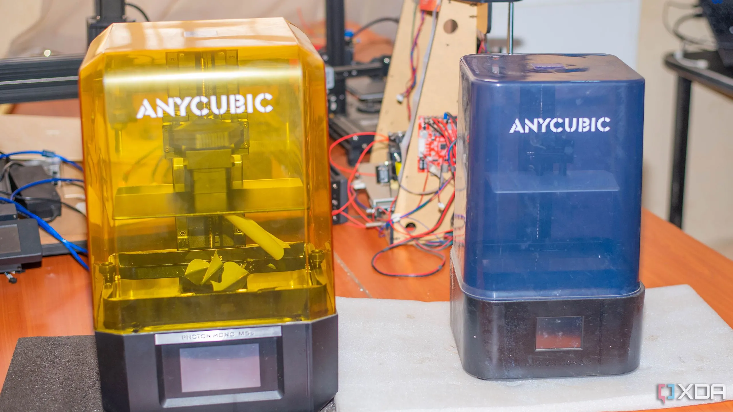 Hai máy in 3D resin Anycubic trên bàn, cho thấy quy trình in resin đòi hỏi thiết bị chuyên dụng