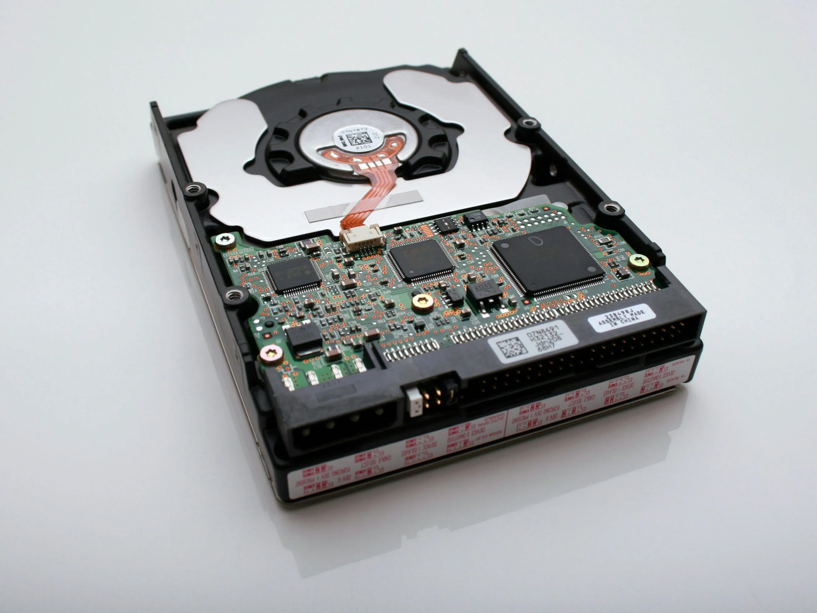 Hình ảnh cận cảnh một ổ cứng HDD với bo mạch điều khiển lộ rõ, tượng trưng cho công nghệ lưu trữ cần thời gian để khởi động và truy cập dữ liệu.