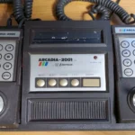 Hình ảnh console game Emerson Arcadia 2001 màu đen với hai tay cầm đặc trưng, biểu tượng cho một thất bại nhanh chóng trong lịch sử console thập niên 80.