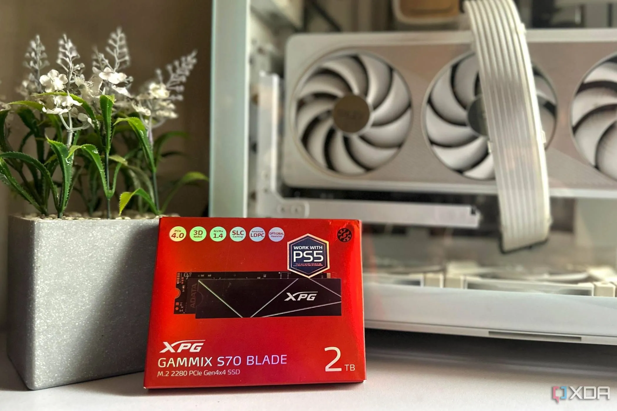 Hộp đựng ổ cứng SSD XPG GAMMIX S70 Blade 2TB màu đỏ bên cạnh vỏ PC