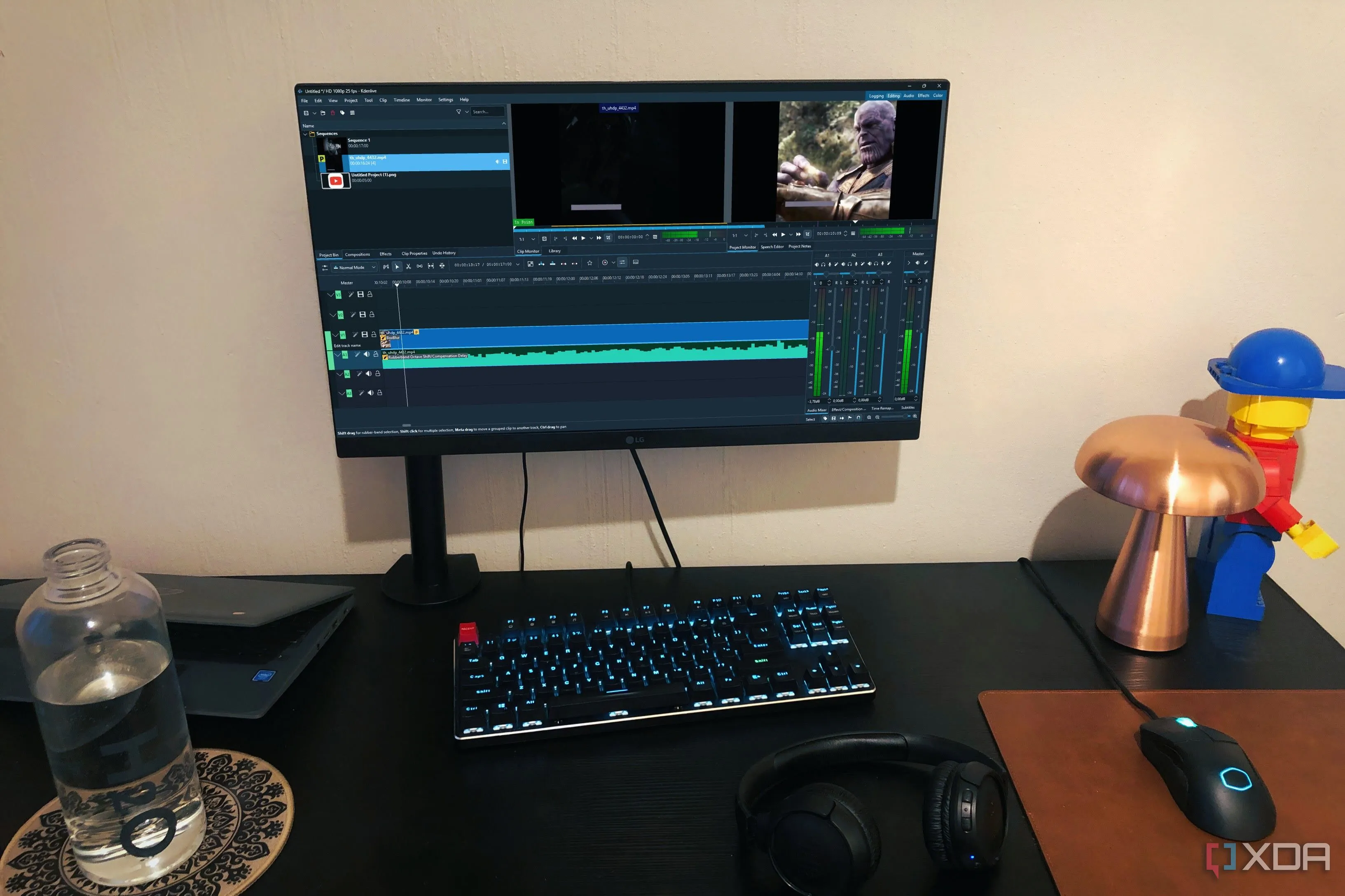 Màn hình máy tính hiển thị giao diện biên tập video Kdenlive trên một bàn làm việc với chai nước, mô hình Lego và Chromebook