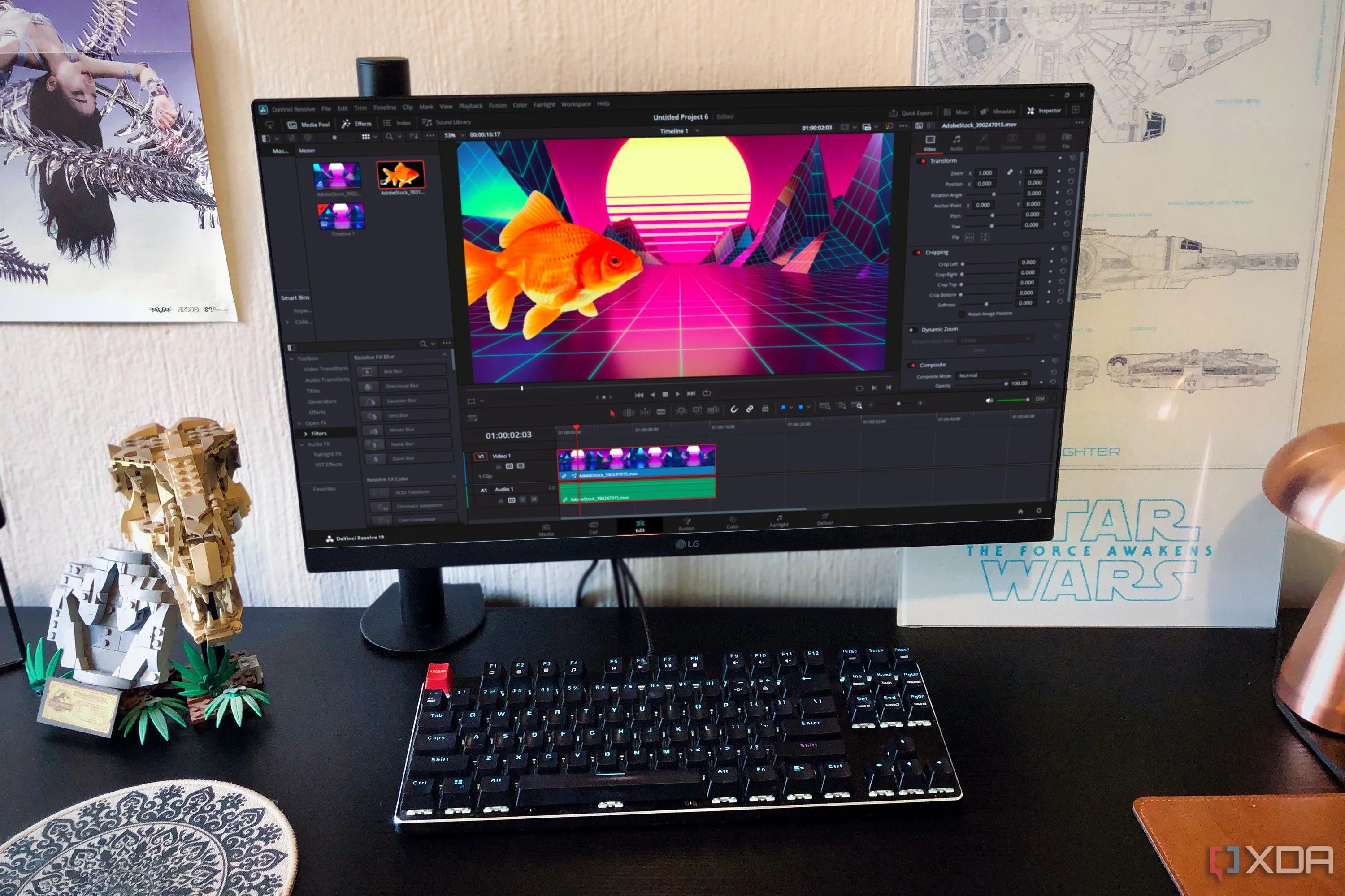 Màn hình máy tính hiển thị giao diện chỉnh sửa DaVinci Resolve với timeline và các công cụ, bên cạnh đèn bàn và mô hình Lego