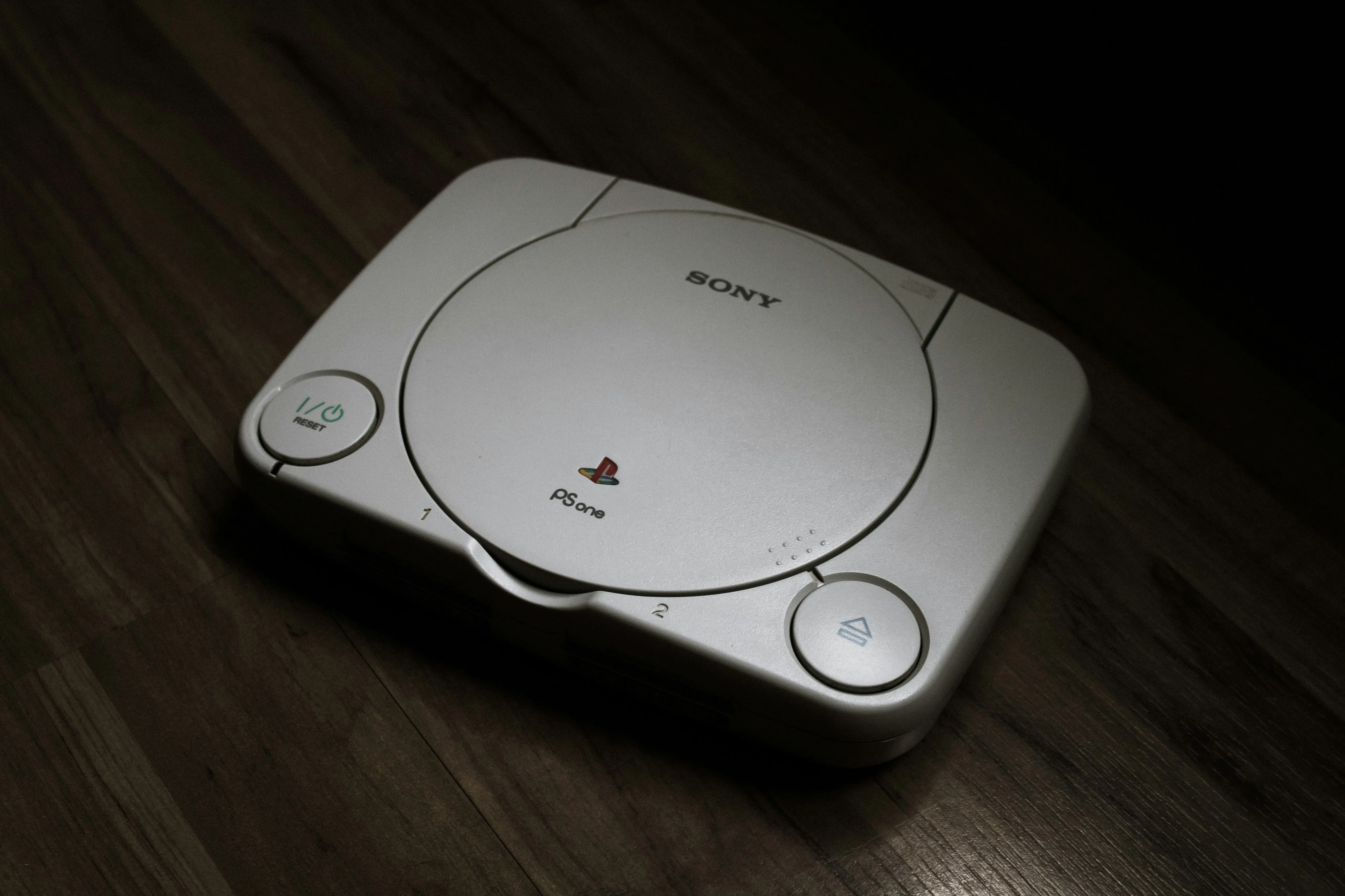 Máy chơi game PlayStation 1 đặt trên sàn gỗ, biểu tượng cho kỷ nguyên console hiện đại