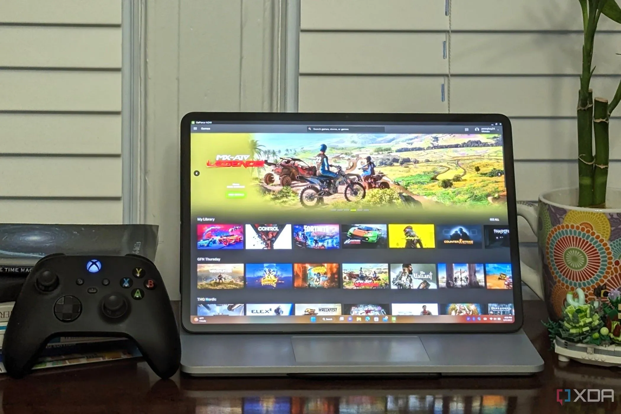 Máy tính xách tay chạy Nvidia GeForce Now Ultimate, cạnh tay cầm Xbox, biểu tượng cho trải nghiệm game trên đám mây