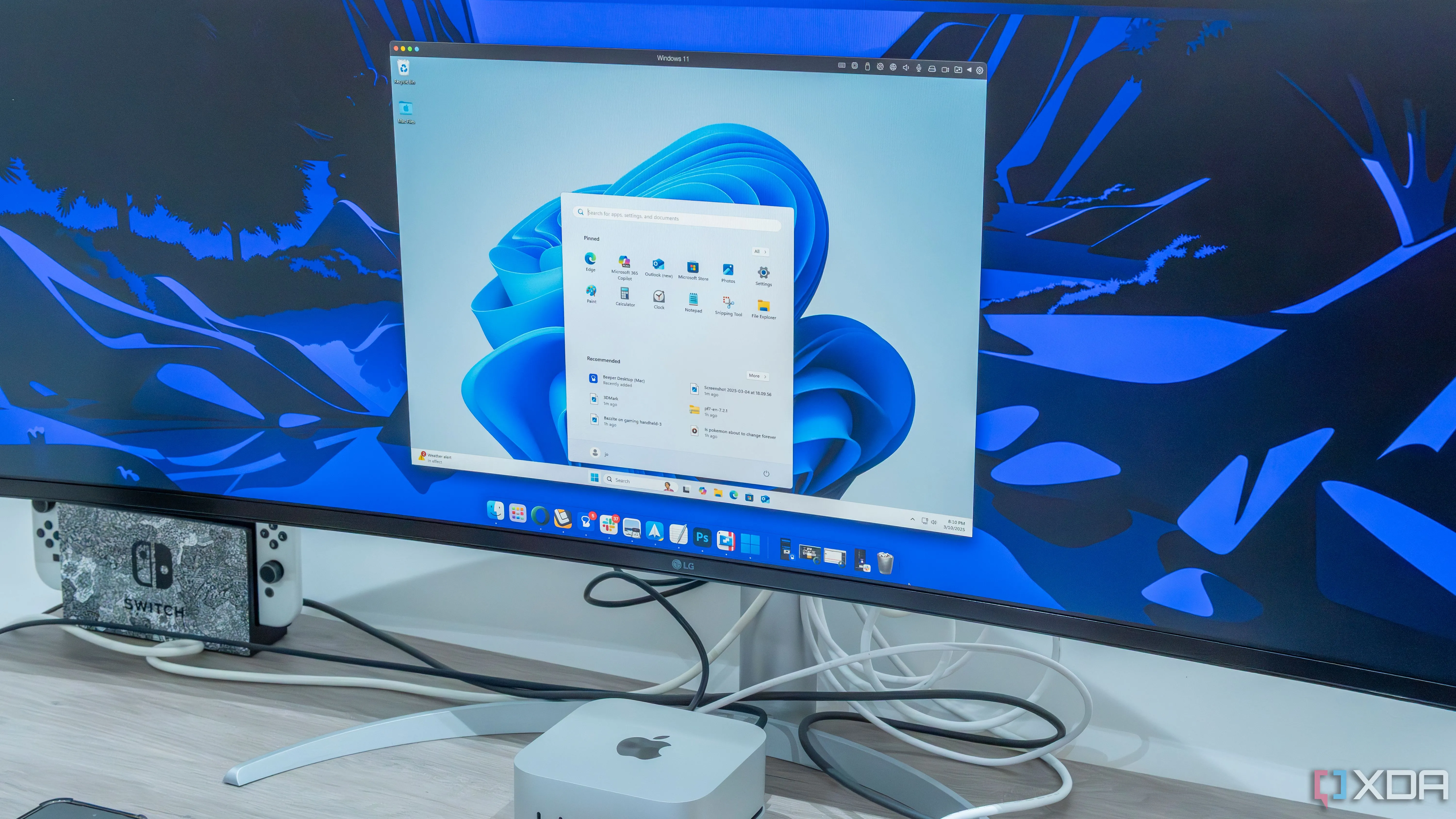 Mô tả: Một máy Mac Mini đặt dưới màn hình, minh họa việc sử dụng máy ảo để chạy các hệ điều hành khác thay vì phân vùng hoặc dual-boot.