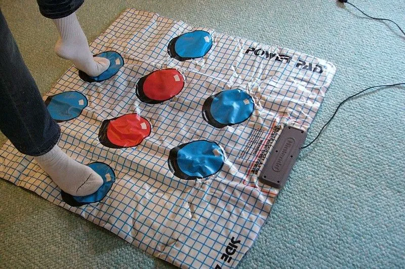 Một người đang đứng trên tấm thảm điều khiển NES Power Pad để chơi game