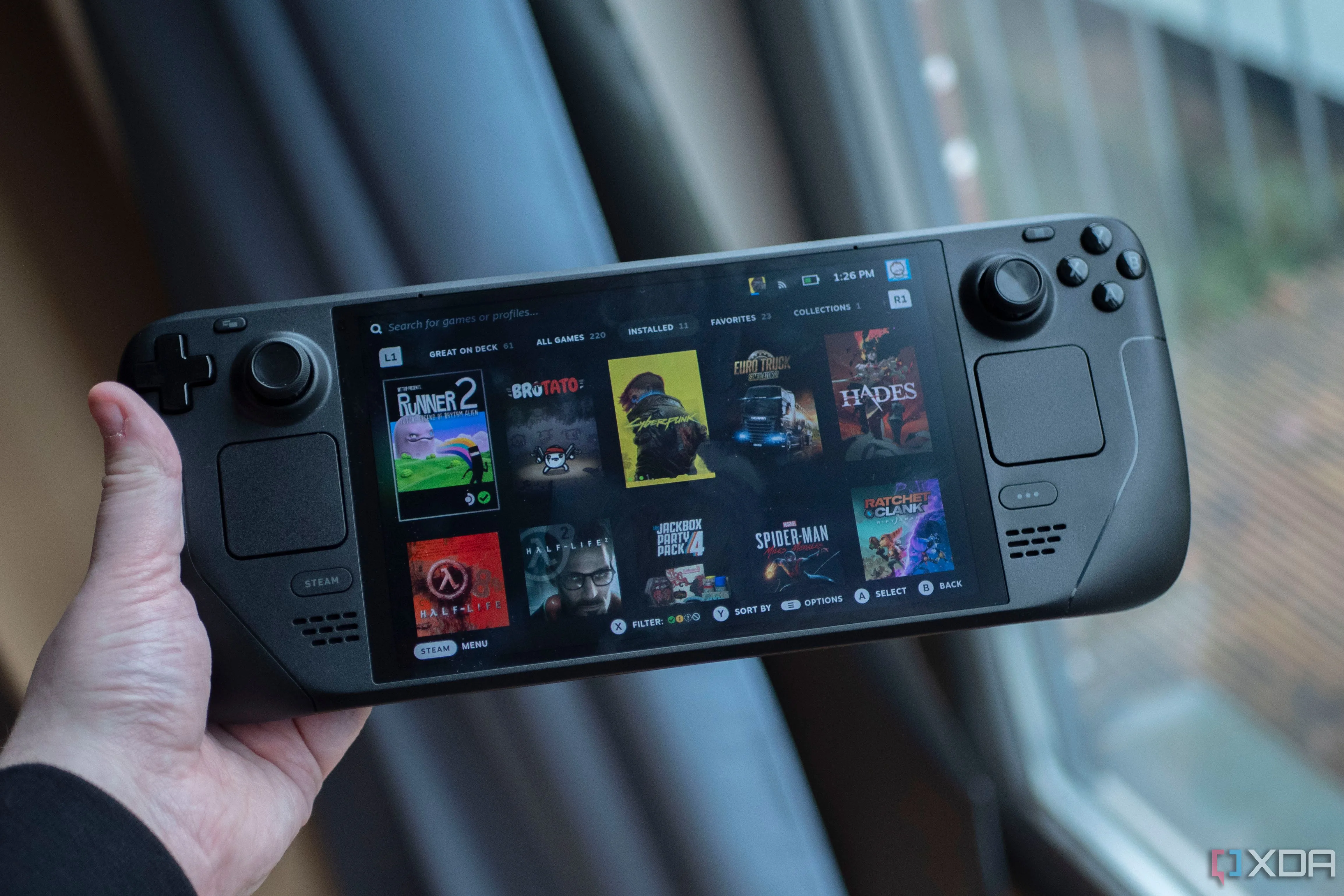 Một người dùng đang cầm thiết bị chơi game cầm tay Steam Deck OLED, gợi ý việc tối ưu download cho cả thiết bị di động.