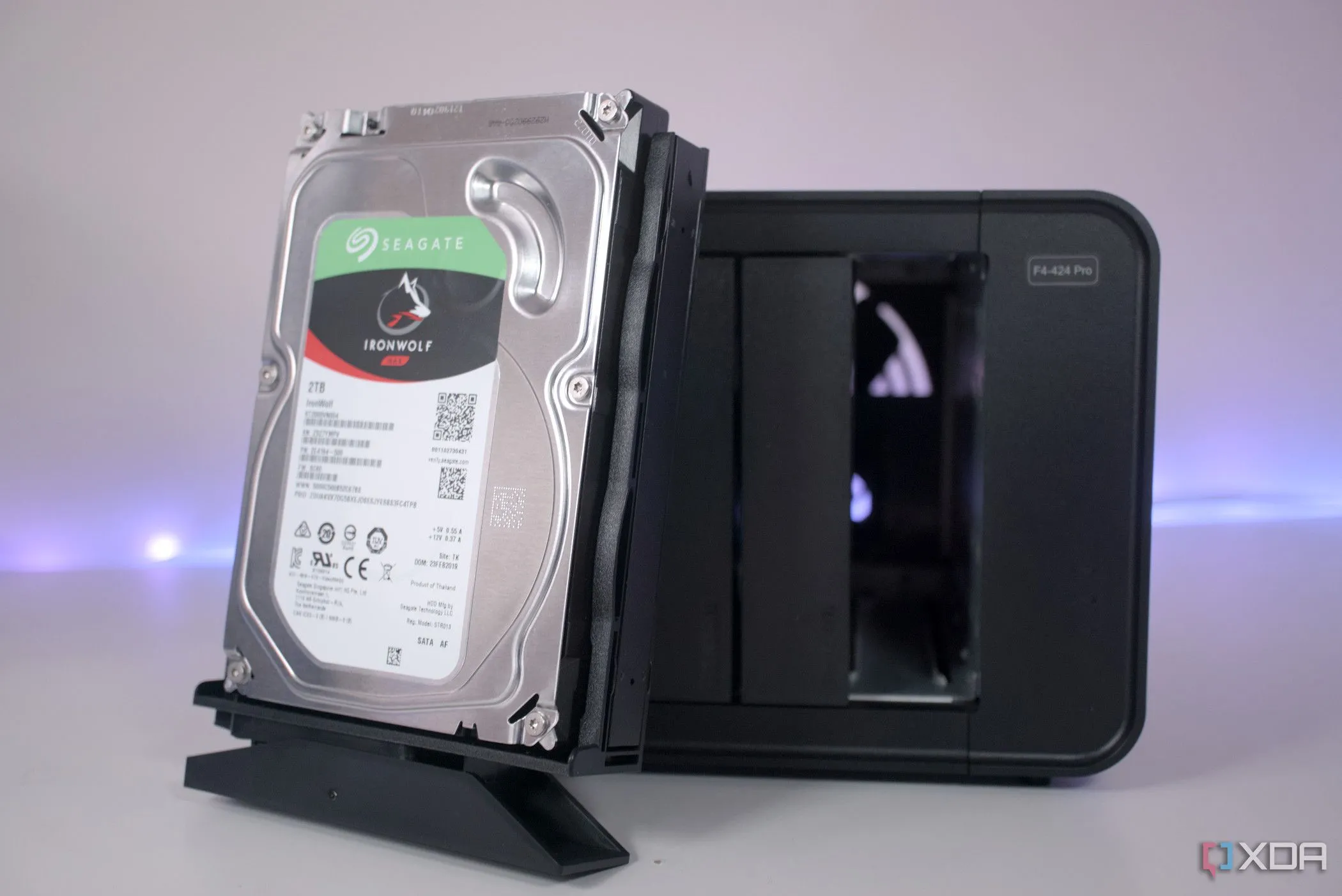 Một ổ cứng HDD truyền thống đặt trước NAS TerraMaster F4-424 Pro, thể hiện sự đối lập về công nghệ lưu trữ với SSD hiện đại.