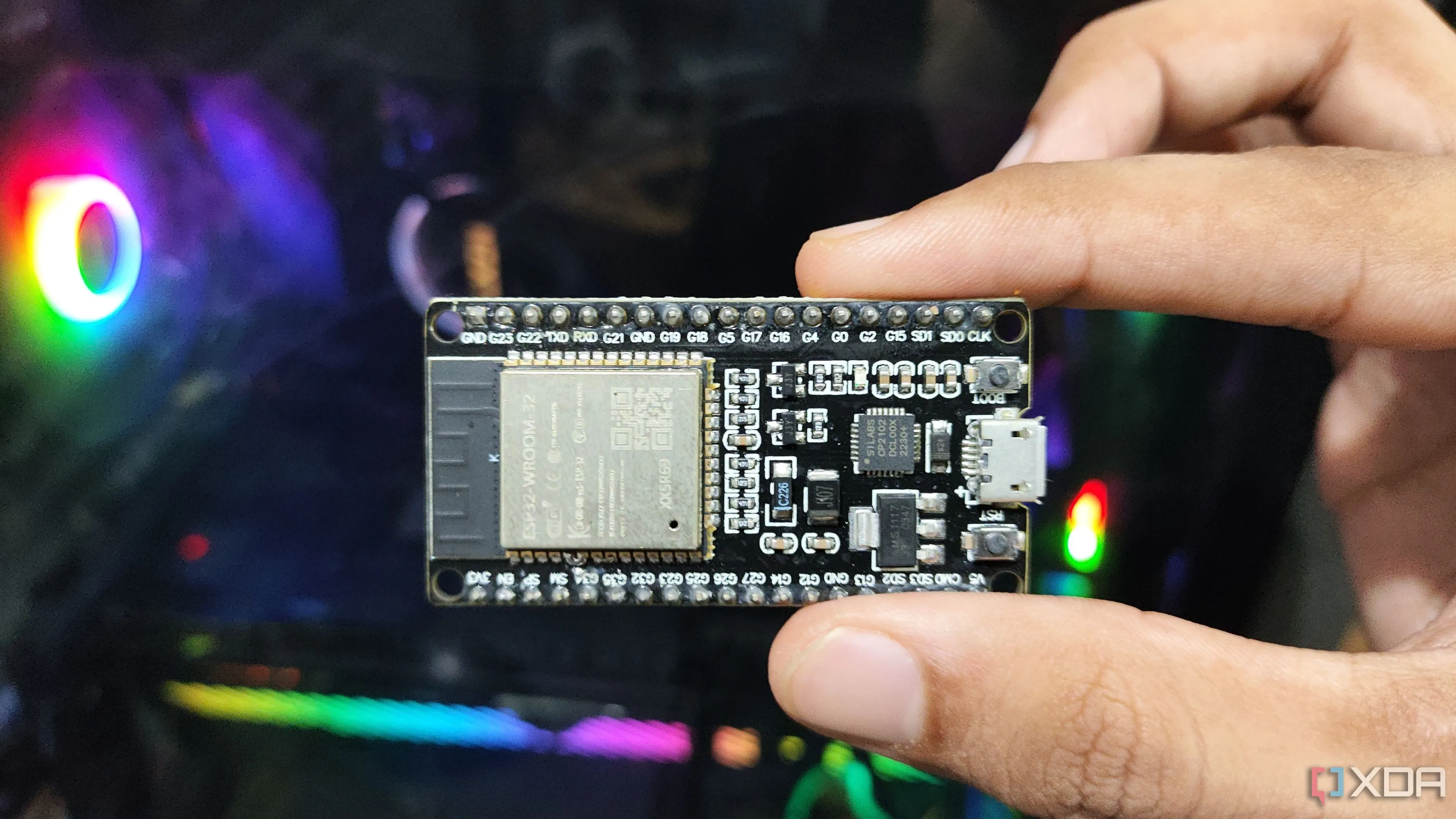 Người dùng cầm vi điều khiển ESP32 trước màn hình máy tính, biểu tượng cho khả năng mở rộng dự án