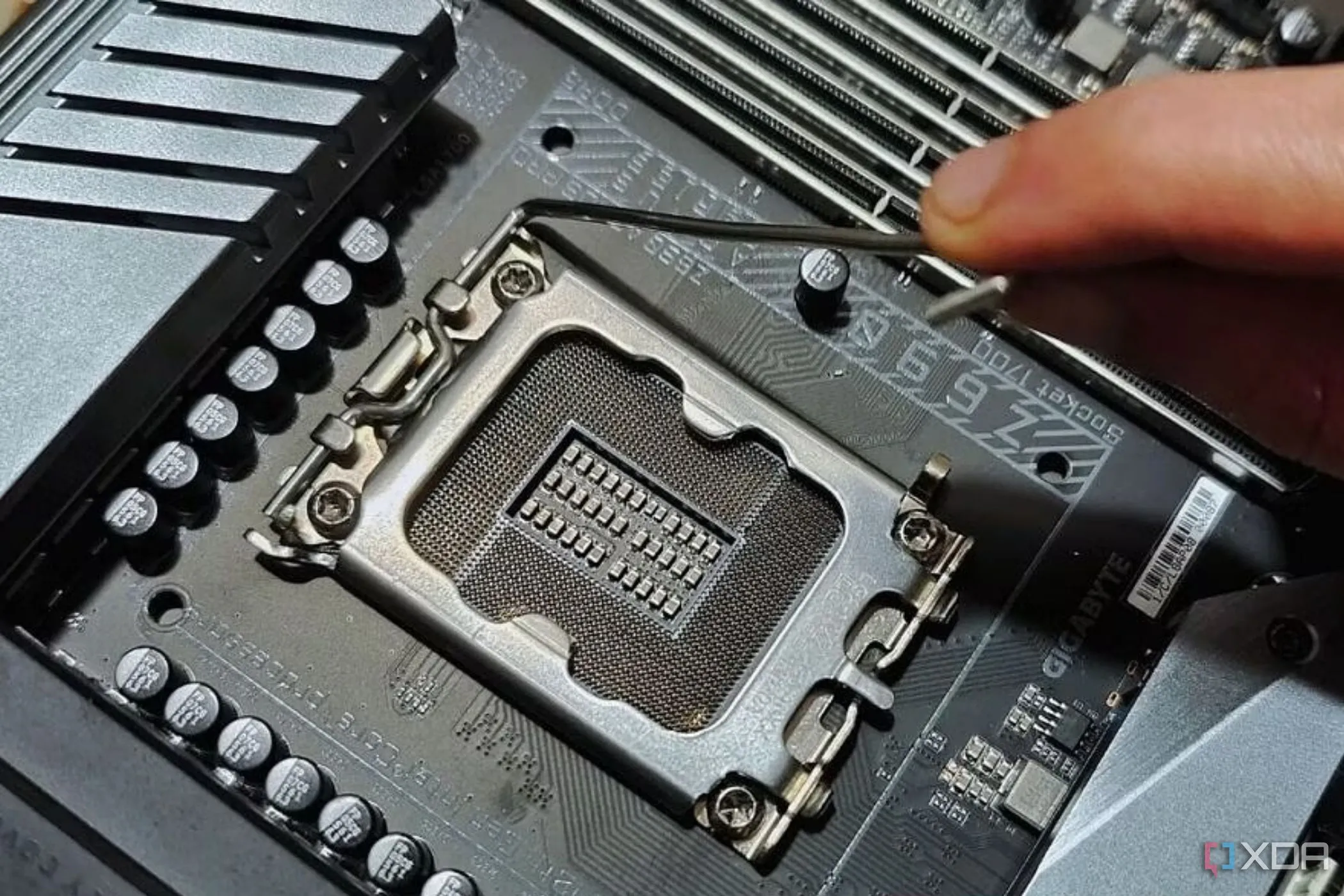 Người dùng đang giữ cần gạt kim loại cạnh socket CPU trên bo mạch chủ, minh họa việc lựa chọn mainboard tương thích CPU