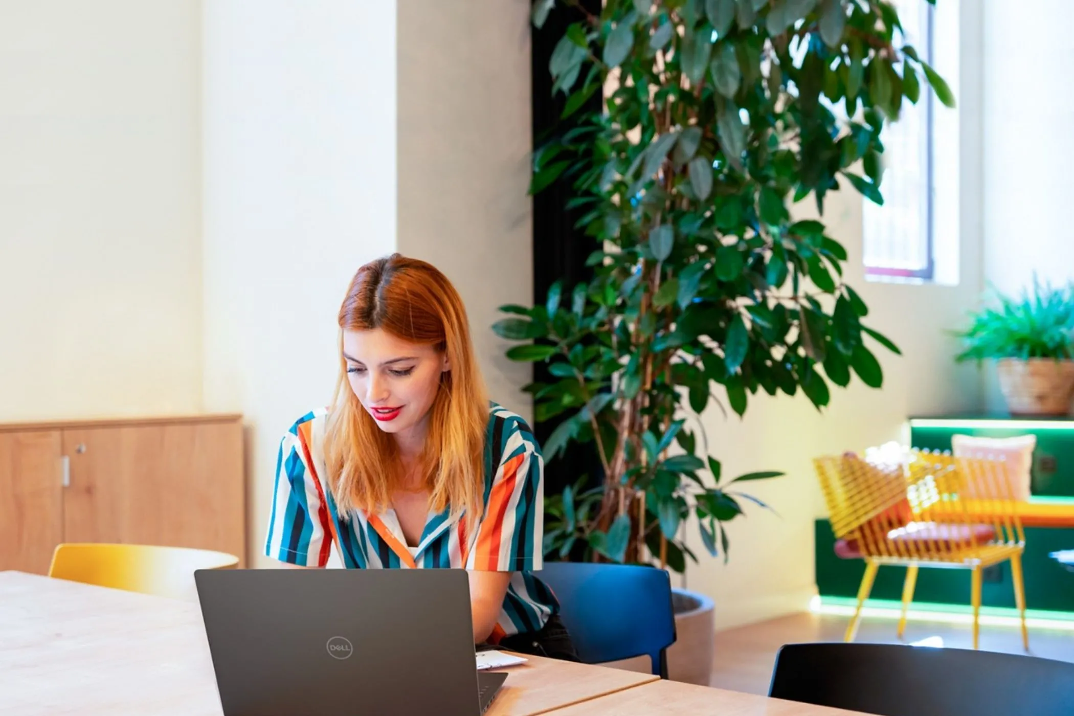 Người phụ nữ làm việc trên laptop Dell tại bàn, tượng trưng cho những chuyên gia cần hiệu suất cao từ SSD Gen 5 trên các máy trạm di động