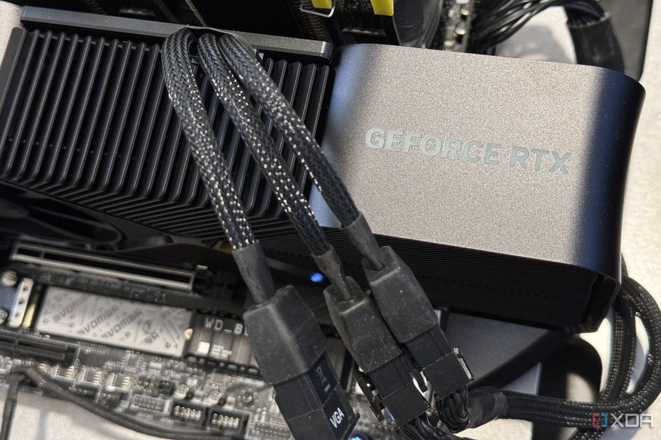 Thẻ đồ họa NVIDIA GeForce RTX 4080 Super với ba cáp nguồn cắm vào bộ chuyển đổi