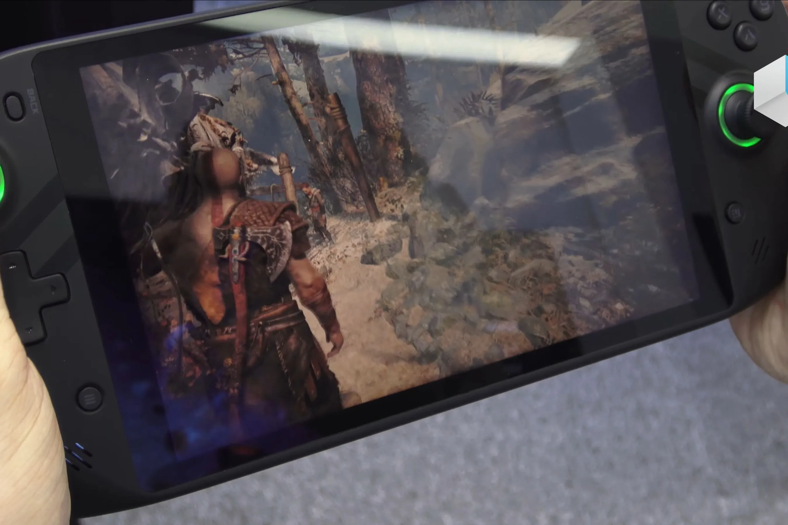 Thiết bị chơi game PC cầm tay hiển thị cảnh Kratos và Atreus trong game God of War, minh họa trải nghiệm trên màn hình nhỏ.