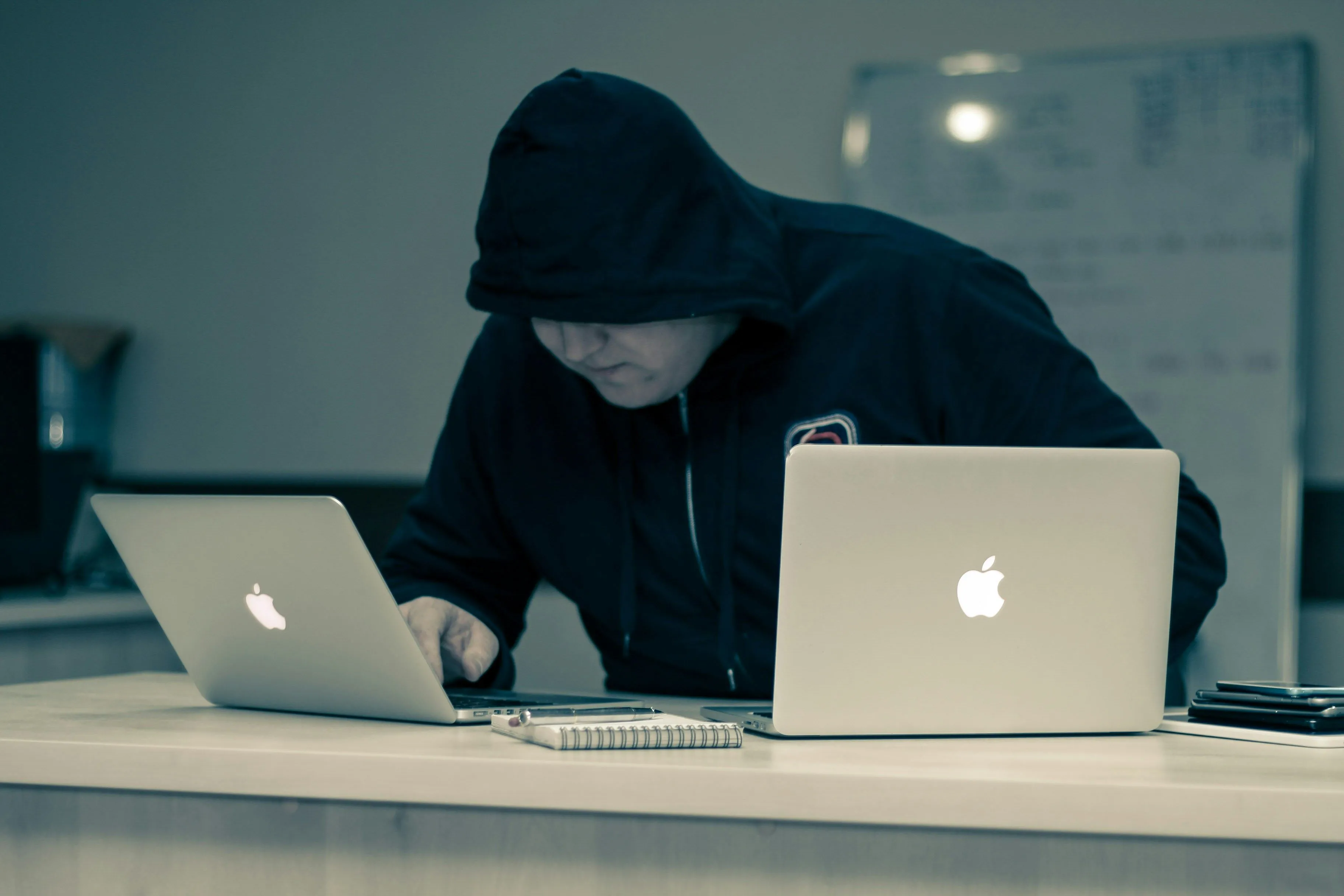 Tin tặc đang gõ bàn phím trên máy tính xách tay Apple, tượng trưng cho các mối đe dọa mạng mà tường lửa phần cứng giúp ngăn chặn.